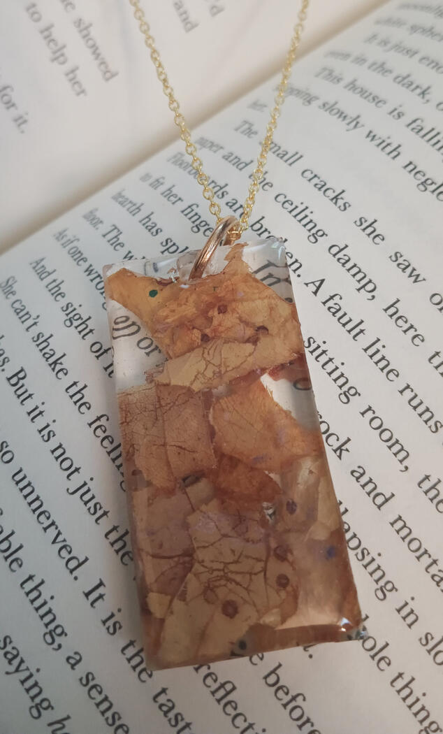 Rectangular resin pendant with dried leaves.